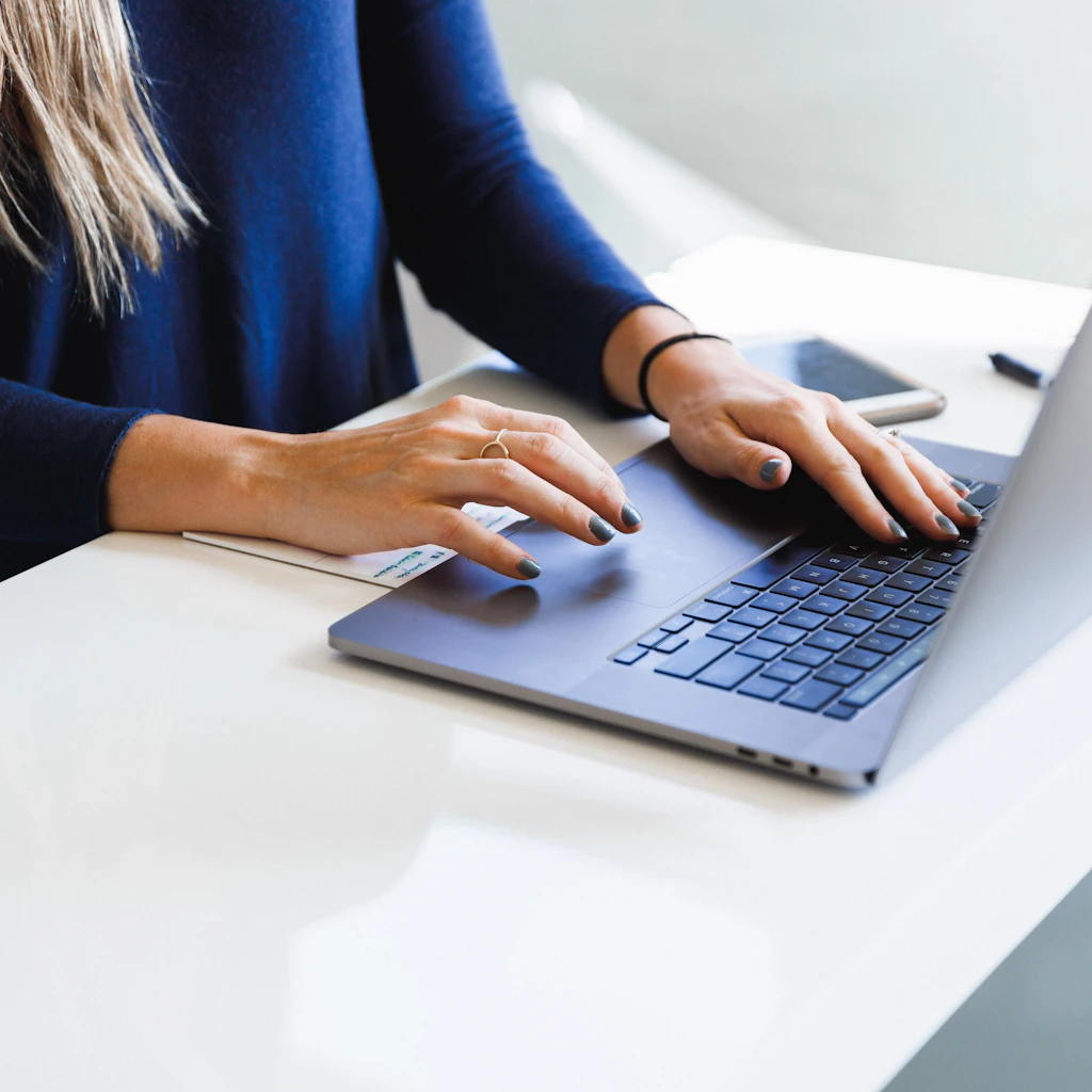 Person typing on a laptop at a bright white desk